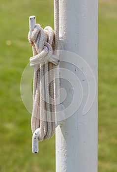 Closeup rope tied on the white iron pole.