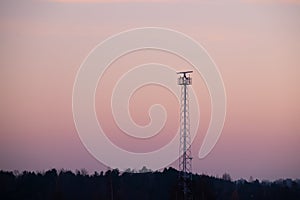 Closeup of a rotating X-band radar on top of a metallic pole against a vivid sky