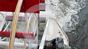 Closeup of rotating red paddle wheel of a cruise boat in motion.