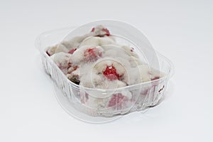 Closeup of rotten moldy raspberry in plastic box isolated on white background