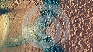 Closeup of rough stone wall surface painted in pink and blue colors