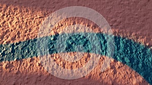 Closeup of rough stone wall surface painted in pink color with blue stroke