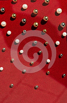 Closeup of round beads sewn on a red fabric
