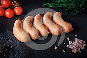 closeup row of five raw short thick sausages with dill and tomatoes