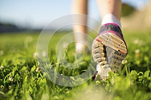 Closeup runner feet running outdoors on the green grass. Fitness.