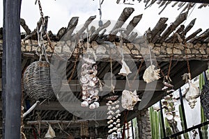 Closeup of rustic stick roof in Mexico with shells and woven baskets hanging from ends of sticks by old ropes and rusty chains wit