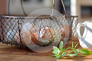 Closeup of rustic wire basket of fresh eggs on the table