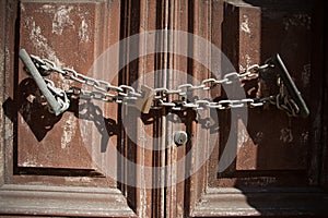 Closeup of a rusty chain with a lock on an old wooden door under the sunlight