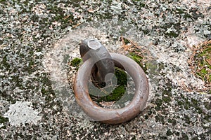Closeup of a rusty old mooring loop fastened in a rock, used to tie up boats in the river