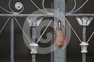 Closeup of a rusty padlock on an old metallic fence in a graveyard