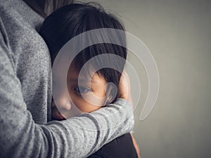 Closeup sad little boy being hugged by his mother at home.