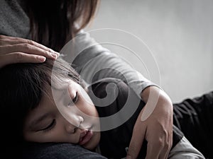 Closeup sad little boy being hugged by his mother at home.