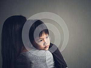 Closeup sad little boy being hugged by his mother at home