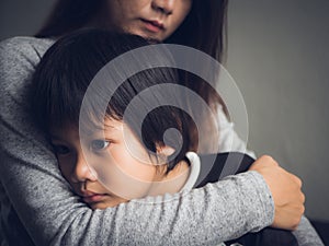 Closeup sad little boy being hugged by his mother at home. photo