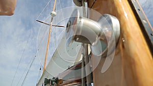 Closeup of the sail of a wooden antique Sail boat navigating in the ocean sunny day showing the wooden parts and