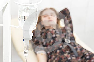 Closeup of saline drip with background Woman patient on the bed get better, when they come for treatment in room hospita