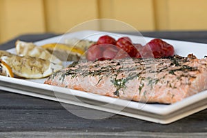 Closeup of a salmon served with cherry tomatoes and lemons