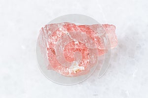 Rough Rhodochrosite crystal on white marble photo