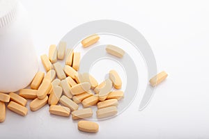 Closeup scattered from white pill bottle orange oval medicine vitamins for pregnancy, pills, drugs isolated on white