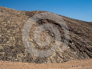 Closeup scene of rough rock mountain texture pattern view with clear blue sky background on unpaved dirt road