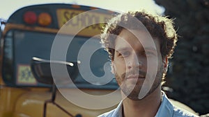 Closeup schoolbus chauffer face at vehicle. Handsome man driver looking camera.