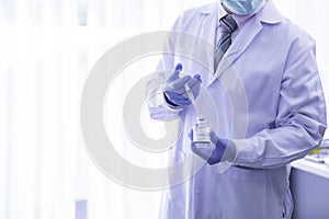 Closeup scientist doctor hand using syringe inject vaccine to medical bottle