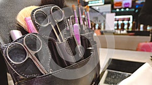 Closeup of scissors combs and make tool in a salon holster pouch .sets of makeup in department store shopping mall.defocus