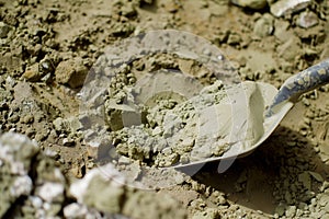 closeup of scoop digging into crumbled dry green clay