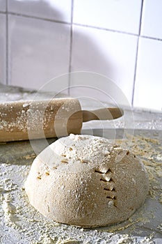 Closeup of a scoured dough sprinkled with flour and a rolling pin on the side photo