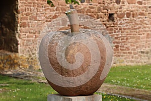 Closeup of a sculpture of an apple against and old stonewalled-building