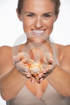 Closeup on sea shell in hands of smiling woman