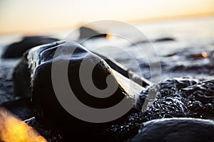 Closeup of sea waves braking on a wet seashore stone summer sunset, water splashes