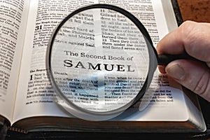 closeup of the second book of Samuel from Bible or Torah using a magnifying glass to enlarge print.