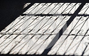 A closeup section Metal fence shadow on the sidewalk