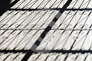 A closeup section Metal fence shadow on the sidewalk