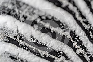 Closeup selective focus on snow packed in an all-weather tire tread.