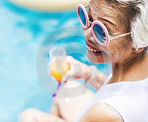 Closeup of senior asian woman with juice by the pool