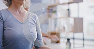 Closeup of a senior woman meditating with mudra hand gesture during a fitness class in a yoga studio. Calm, relaxed and