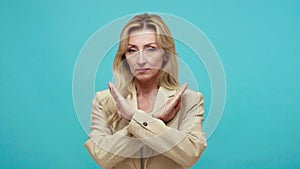 Closeup serious sceptic adult woman in business style jacket showing no gesture, crossing hands on chest, rejection, ban, no way