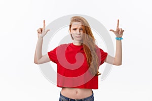 Closeup of serious strict young woman wears red shirt looks stressed and pointing up with finger isolated over white