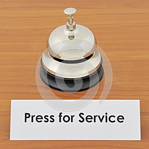 Closeup of service bell and sign on wooden desk