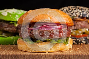 Closeup of set of three mini homemade Burger with marble beef and vegetables on a wooden Board