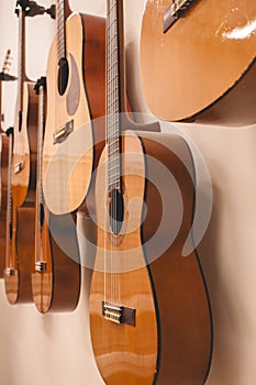 Closeup of several Spanish guitars hanging on the wall, after a music class