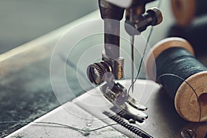 Closeup of sewing needle. Spool of thread on working part of antique sewing machine