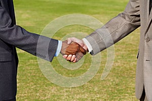 Closeup, shaking hands and business men on grass for b2b agreement, welcome and teamwork. Businessman, hand shake and