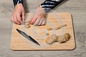 Closeup a shaping sweet cookies vanilla rolls from raw nutty dough on wooden cutting board