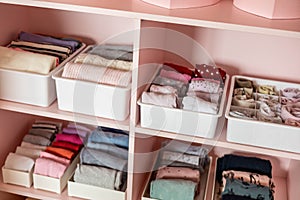 Closeup shelves pink female childish closet with neatly folded clothes Marie Kondo vertical storage