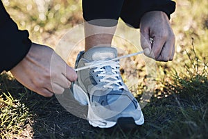 Closeup, shoes ad man runner in a park for training, sports or morning cardio preparation. Hand, sneaker and athletic