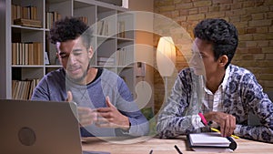 Closeup shoot of african american and indian male students having a funny discussion together. One is using on the