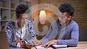 Closeup shoot of african american and indian male students learning together. Two friends playing a tic tac toe and